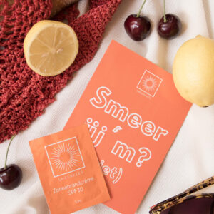 Zonnebrandcrème sachets van Smeerkees Zonnebrandcrème naast wat fruit.