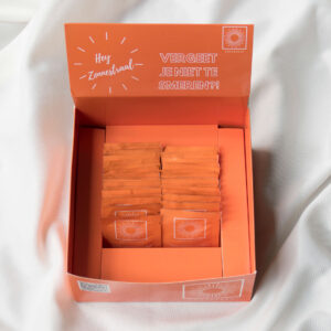 Doos vol zonnebrandcrème sachets van Smeerkees Zonnebrandcrème.
