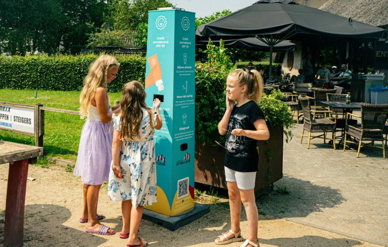 Meisjes smeren zich in met zonnebrandcrème bij de Smeerkees Zonnebrandpaal in Etten-Leur