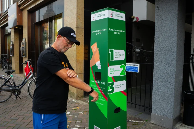 Man smeert zijn arm in bij een Smeerkees zonnebrandpaal in gemeente Roosendaal